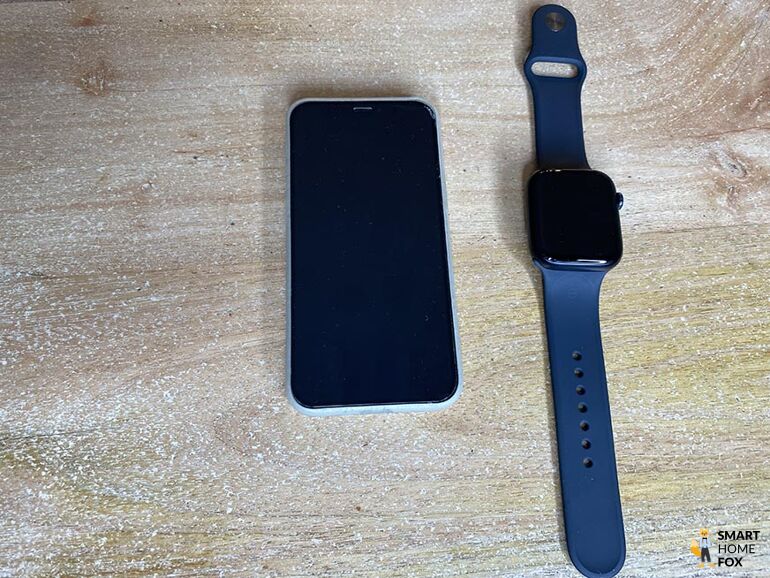 Часы Apple Watch, лежащие на столе рядом с iPhone.