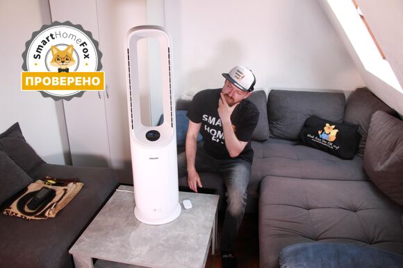 Philips Air Performer Series 7000 стоит на журнальном столике, а рядом с ним сидит эксперт Smart Home Fox Алекс и с интересом рассматривает очиститель воздуха и башенный вентилятор 2-в-1.