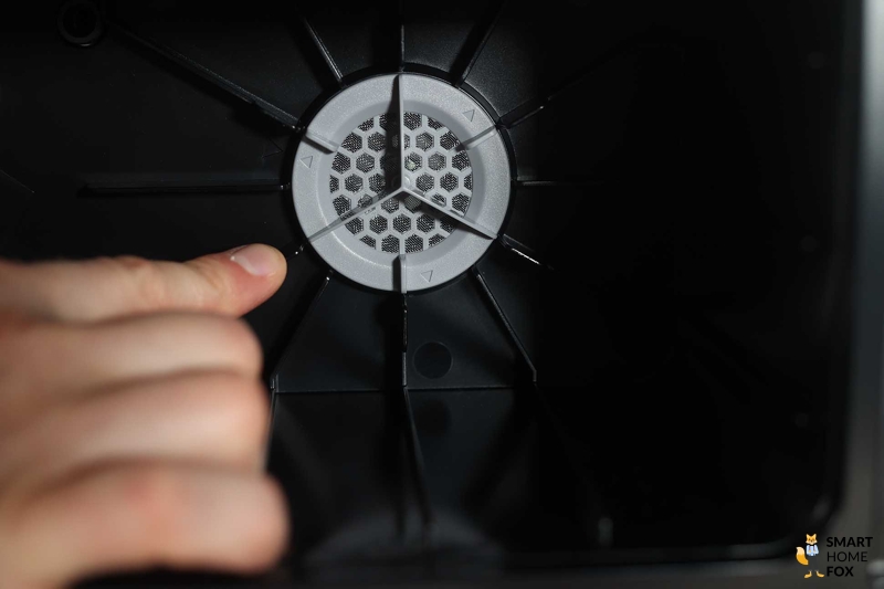 Палец указывает на фильтр в станции Roborock Q Revo.
