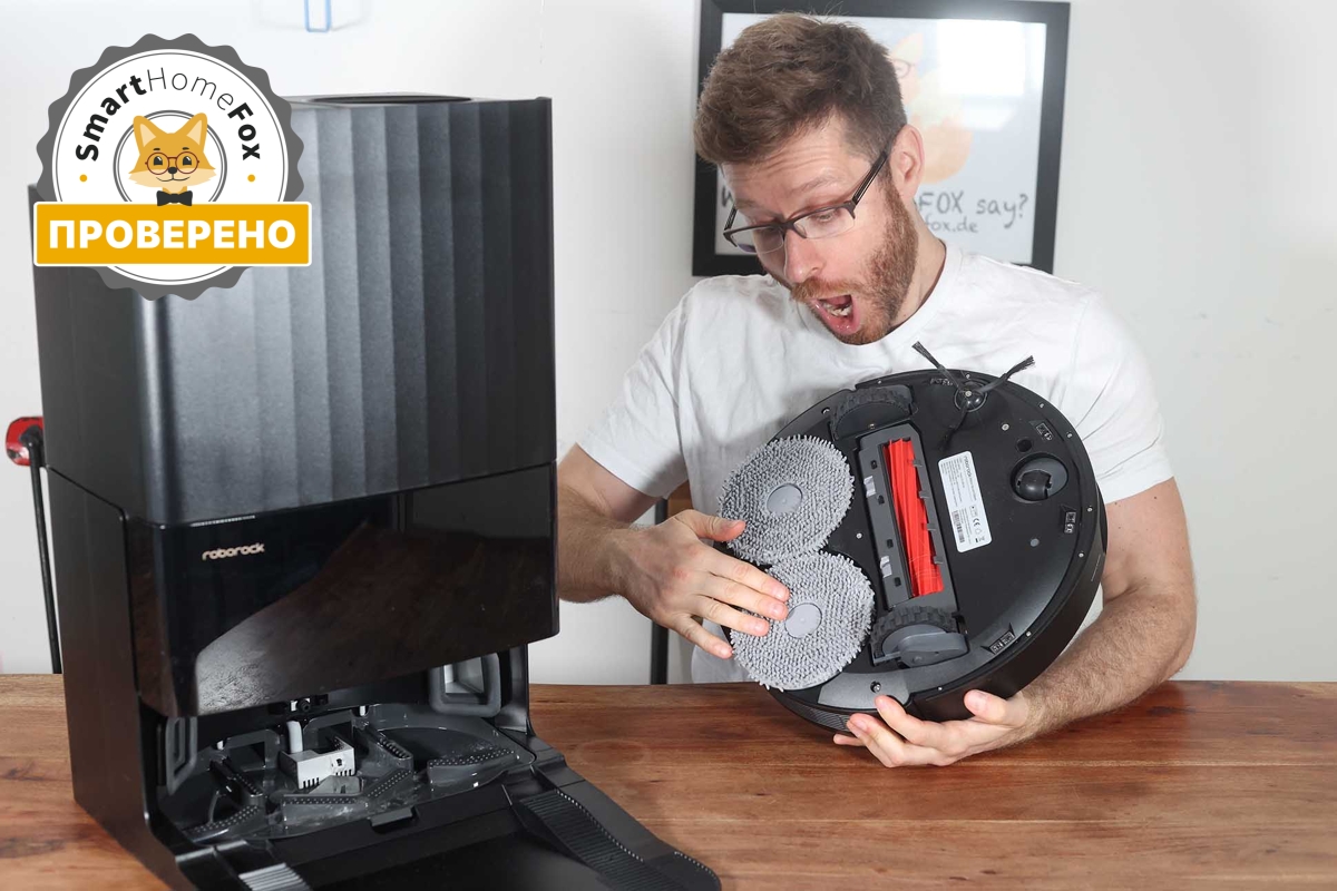 Roborock Q Revo стоит на столе, а сотрудник компании Smart Home Fox осматривает его.
